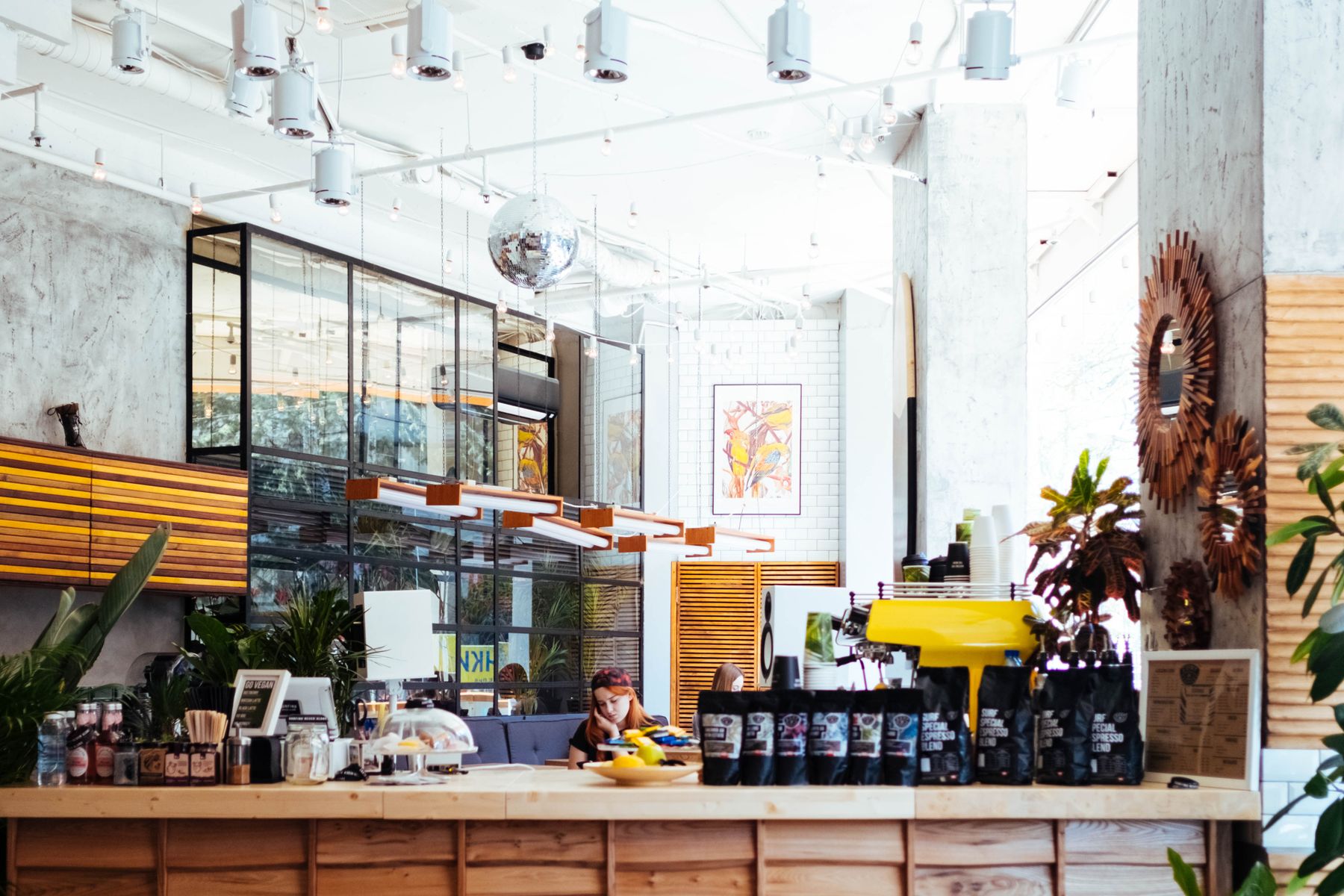 Bright café interior with a service counter, shelves and plants