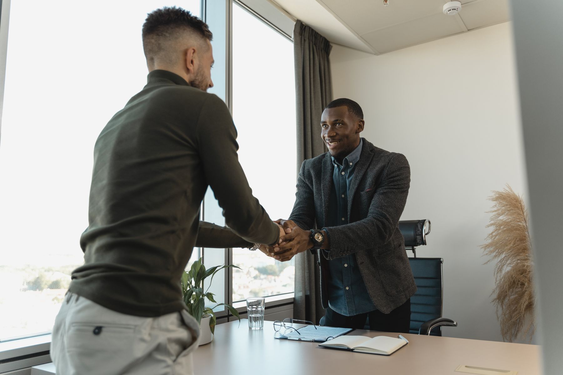 Recruitment consultant greeting a client with a handshake in a bright meeting room