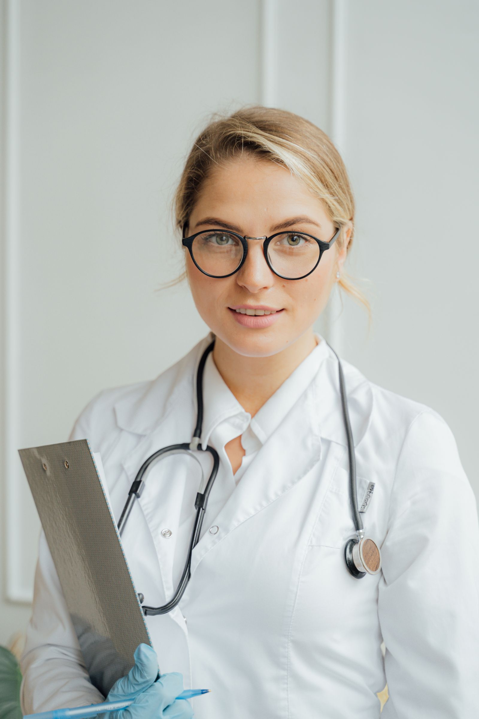 Doctor in a white coat holding a clipboard in a consulting room
