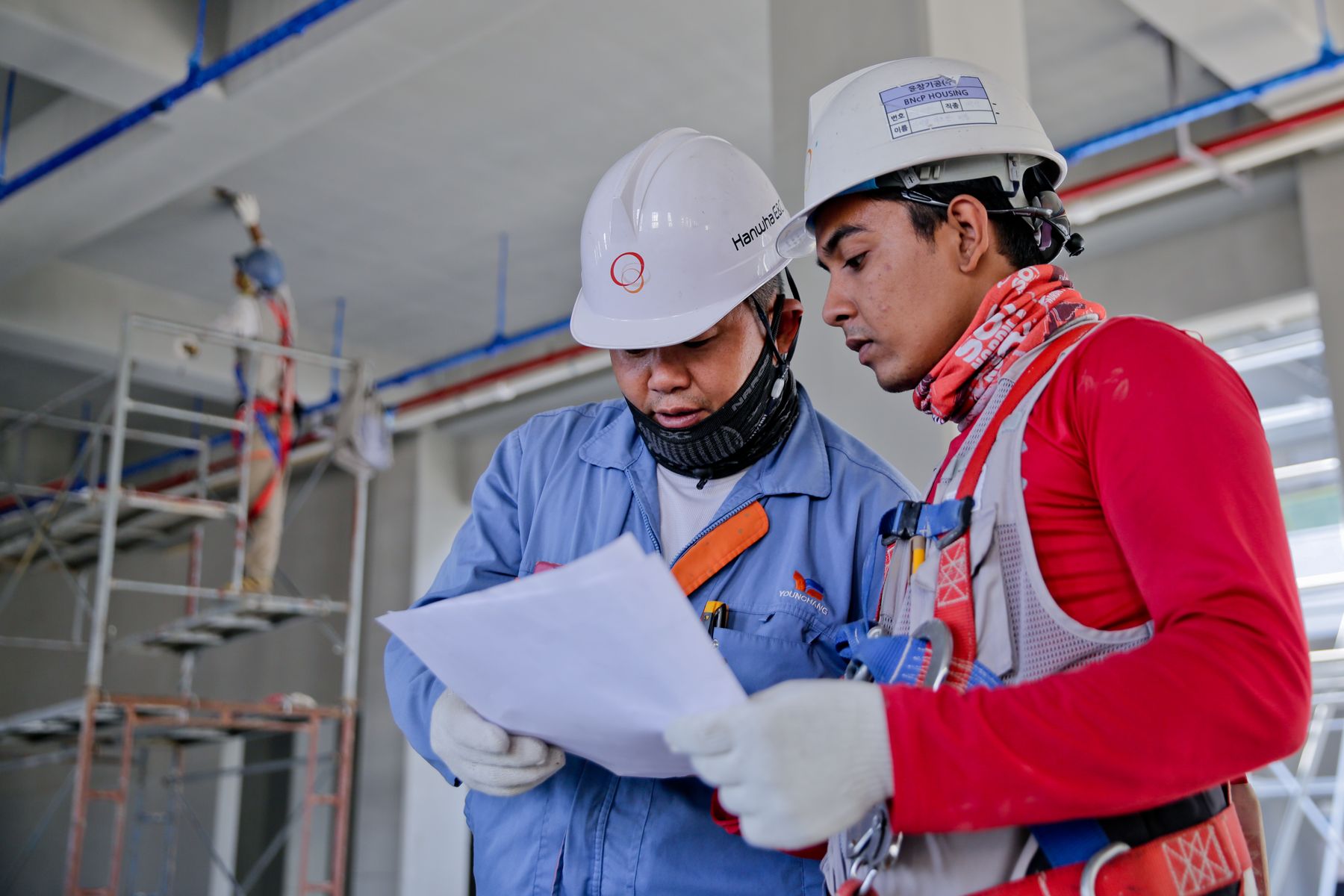 Two engineers in hard hats reviewing drawings together on a construction site