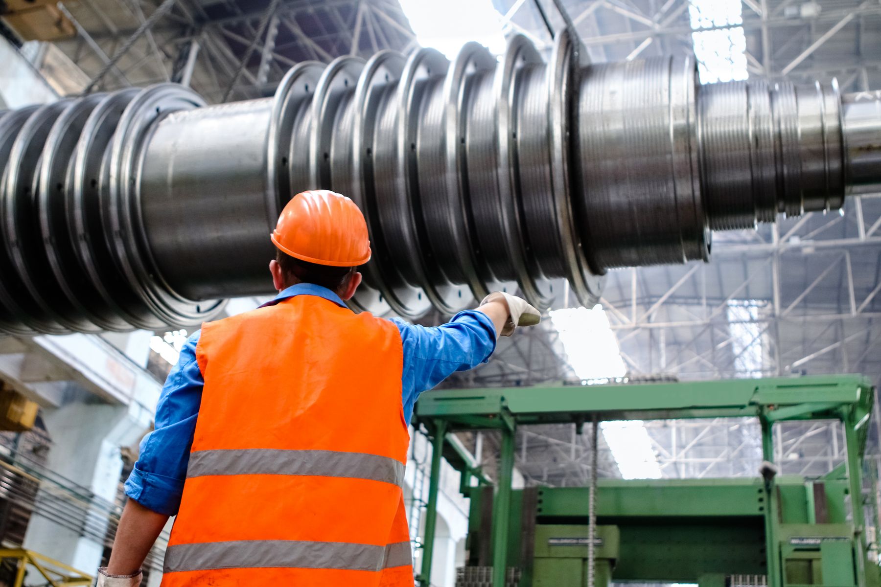 Worker inspecting a machined metal component in a workshop