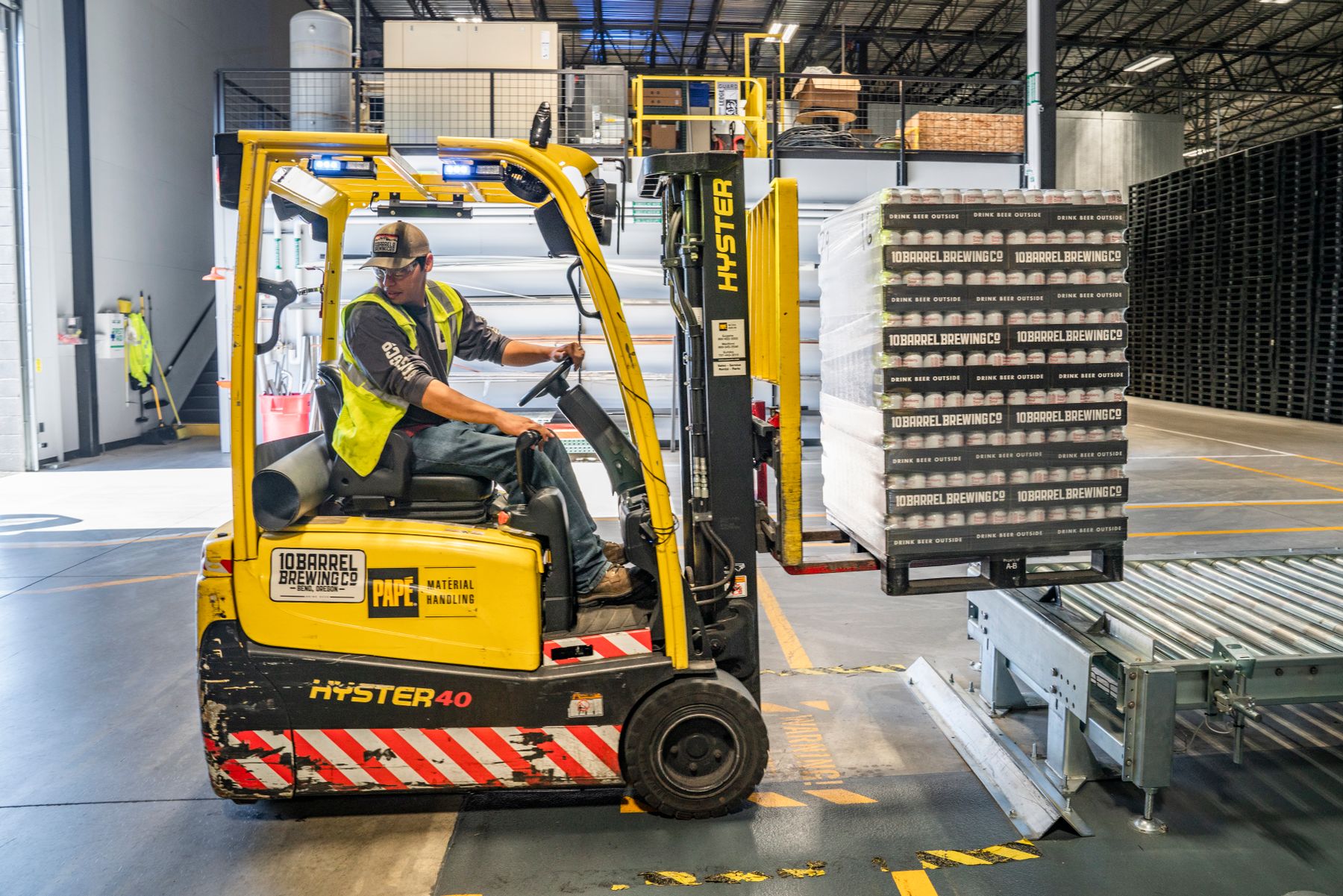 Forklift moving crated machinery at a warehouse loading dock