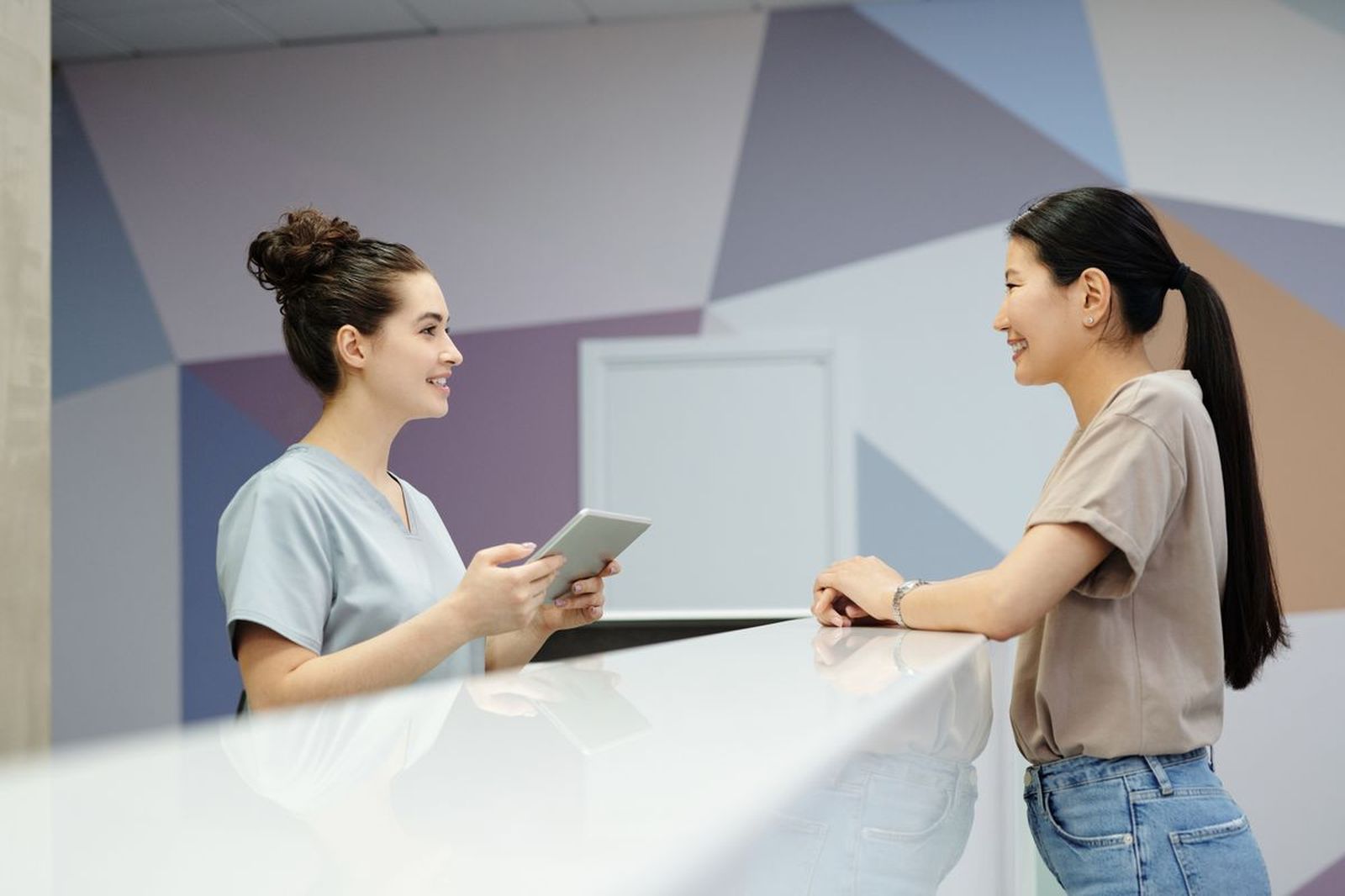 Hospital reception staff helping a visitor at the front desk