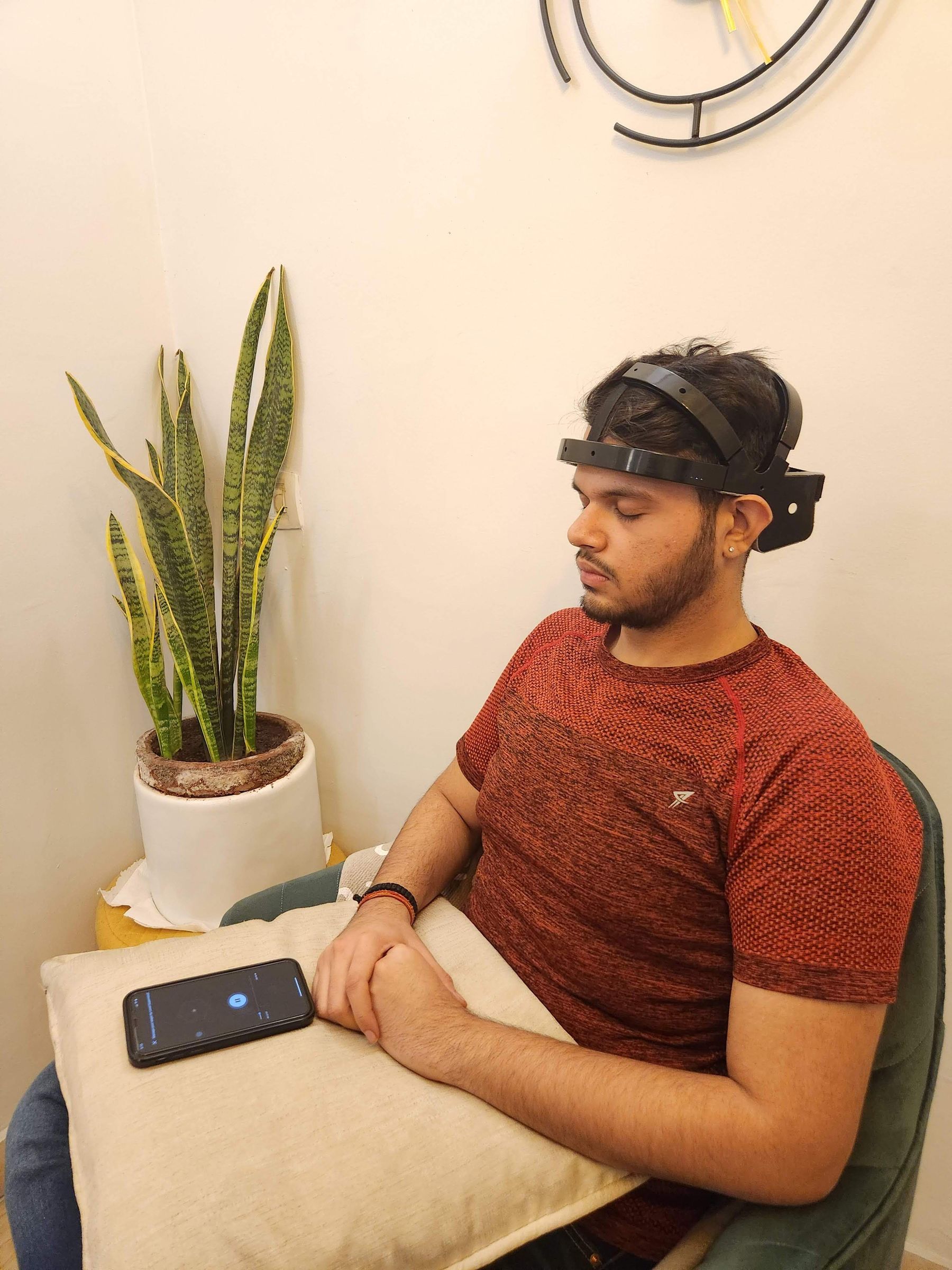A person seated in a clinic room wearing an EEG headband during a neurofeedback training session