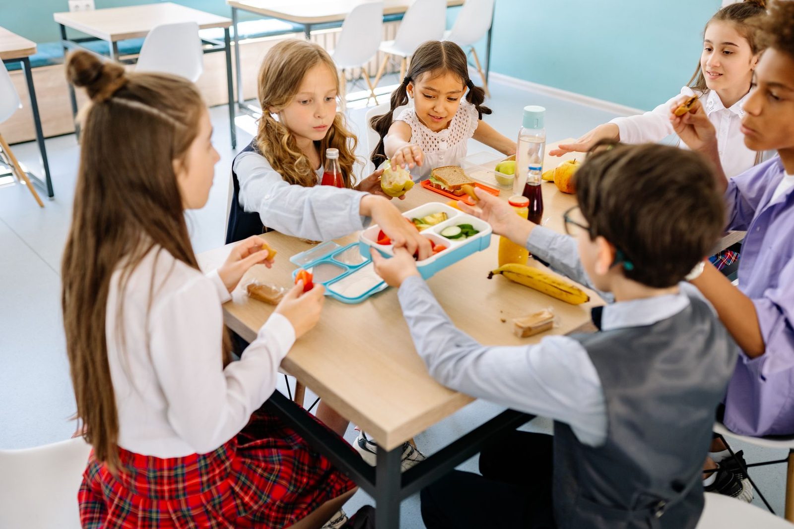 Primary school pupils working together at a classroom table with books and pencils